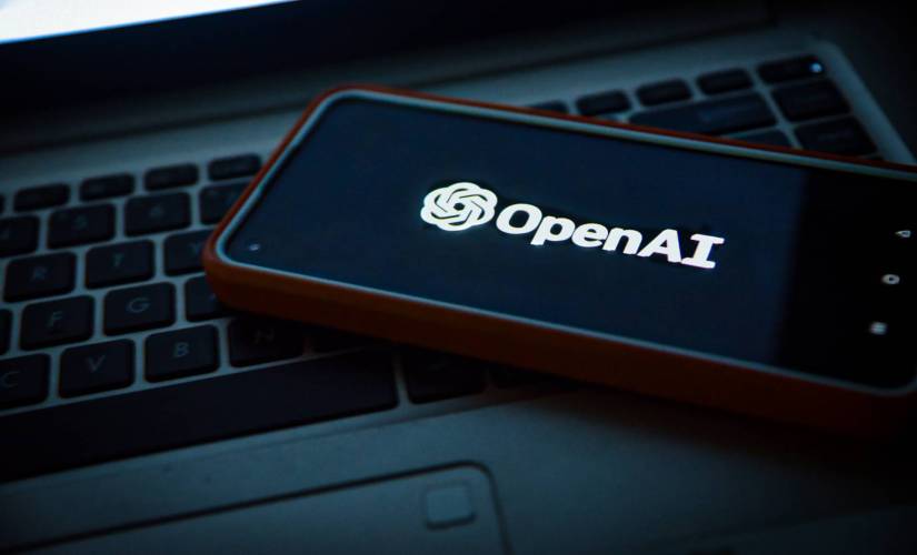 Uma imagem de um telefone colocado em um laptop. O telefone tem o logotipo OpenAI na tela. A empresa por trás do ChatGPT fechou um acordo com Axel Springer